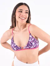 Top de bikini triangular con estampado floral en tonos azul, blanco y fucsia. Tiene tirantes finos fucsia y abertura en el centro del busto.