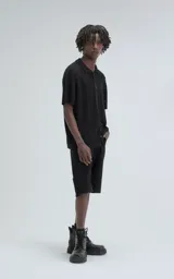 Camisa negra de tejido de punto calado con diseño de zigzag, cuello polo, manga corta y cierre frontal con botones.