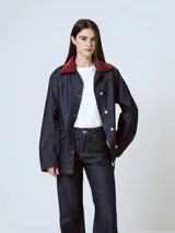 Chaqueta de denim azul oscuro con cuello de piel sintética color borgoña, cierre frontal con botones a presión, bolsillos de parche con solapa en el pecho y bolsillos laterales.