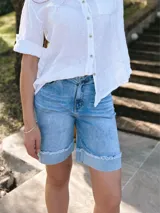 Bermuda de jean celeste con lavado claro, corte a la rodilla y ruedo desflecado.