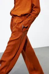Pantalón palazzo color ladrillo confeccionado en lino 100%, de tiro medio con cintura ajustable con cordones, bolsillos laterales ocultos en costura y pierna ancha.