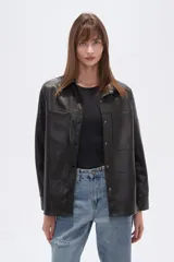 Sobrecamisa negra de efecto cuero, con cuello camisero, botones frontales y dos bolsillos de parche con solapa en el pecho. Presenta un calce holgado.