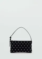 Bolso negro rectangular con tachuelas plateadas, asa corta y cierre de cremallera.