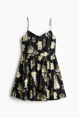 Vestido corto negro con estampado floral blanco y amarillo, de breteles finos, escote corazón, cuerpo entallado, espalda fruncida, cintura marcada con elástico y falda con vuelo.
