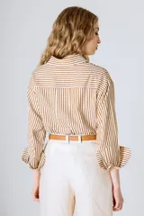 Camisa holgada de manga larga con rayas verticales verdes y blancas. El ruedo es más largo en la parte trasera.
