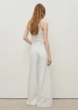 Pantalón de jeans blanco, tiro alto, corte wideleg (pierna ancha) y largo completo. Presenta cinco bolsillos y cierre frontal con botón y cremallera.