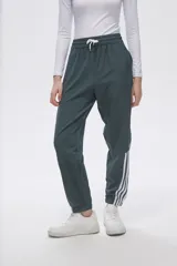Pantalón de jogging color celeste con cintura elástica ajustable con cordón y puños elásticos. Presenta tres tiras verticales blancas en la parte inferior de la pierna.