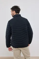 Campera capitoneada liviana color azul marino, con cuello alto y dos bolsillos exteriores con cierre. Interior del cuello a contratono.