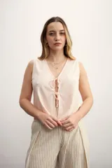 Chaleco color rosa pálido con escote en V y lazos frontales.