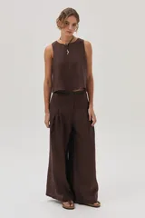Conjunto de dos piezas color marrón oscuro, compuesto por un top sin mangas de corte recto y un pantalón de lino de tiro alto, pierna ancha y pinzas frontales.