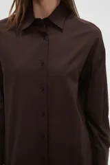 Camisa blanca de algodón con cuello clásico, corte holgado, cierre frontal con botones y mangas largas.