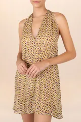 Vestido corto con estampado abstracto en tonos amarillos, marrones y violetas, con cuello halter que se ata al cuello y espalda descubierta.