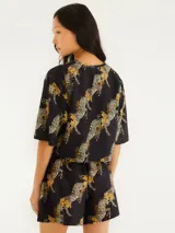 Short negro con estampado de cebras y hojas color ocre, de tela liviana y cintura elástica.
