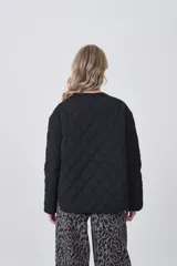 Campera acolchada negra, con diseño capitoné en rombos, cuello redondo y cierre frontal con botones a presión. Posee bolsillos delanteros amplios.