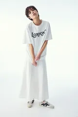 Remera blanca de algodón con cuello redondo y mangas cortas. Estampado frontal con la palabra "London" en letras negras con diseño ornamentado.
