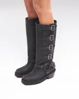 Botas de caña alta color negro, confeccionadas en cuero vacuno con apliques de herrajes metálicos y plantilla entera para mayor confort. Taco de 6 cm.