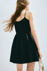 Vestido corto negro de popelina de algodón, con breteles spaghetti ajustables, escote redondo y abertura con tiras finas en el frente.