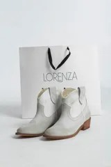 Botines de cuero color gris claro, estilo texano, con puntera fina, caña baja y taco de madera.