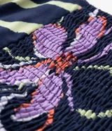 Blusa larga de viscosa con estampado floral, escote en V con lazo, breteles medianos y abertura frontal.