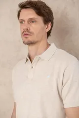 Chomba azul marino de piqué con cuello clásico, tapeta de dos botones y logo de pájaro bordado en color rosa en el pecho.