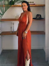 Vestido largo color terracota con hilo lurex dorado, escote halter con borde de cuentas y aberturas laterales profundas. Presenta un corte imperio con frunces en el busto.