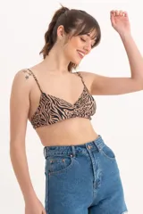 Top de bikini con estampado animal print en tonos beige y negro, con breteles finos y diseño cruzado en el centro del busto.