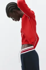 Chaqueta de punto roja con escote pico y manga larga. Tiene vivos laterales combinados a contraste y cierre frontal con botones forrados a tono.