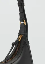 Cartera de hombro estilo hobo en color negro, confeccionada en material sintético con acabado liso. Presenta un diseño de media luna con cierre de cremallera y correa ajustable con hebilla metálica.