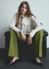 Pantalón de vestir verde oliva de tiro bajo y corte acampanado. Con trabillas, bolsillos traseros de ribete y cierre oculto de botón, gancho y cremallera.