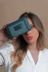 Billetera mediana color verde azulado de símil cuero con textura croco. Tiene compartimento interior con tarjeteros, cierre interior y monedero con cierre alrededor.