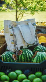Bolso tipo shopper color crema con textura croco, doble asa corta y apliques metálicos circulares.