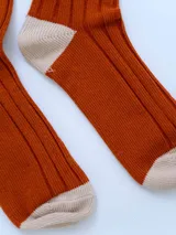 Par de medias acanaladas color ladrillo con puntera y talón en color crema y puño superior en color rojo.