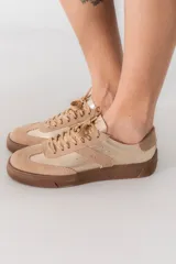 Zapatillas urbanas color beige con detalles en marrón y suela marrón.