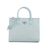 Cartera tipo shopper grande color celeste, confeccionada en rafia y cuero sintético. Tiene doble asa de mano, correa bandolera regulable y cierre superior. El interior está forrado en tela de algodón y poliéster, y cuenta con un bolsillo con cierre y dos bolsillos abiertos.