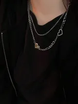 Collar doble de cadena plateada, con un dije de corazón dorado y un dije de corazón calado plateado.