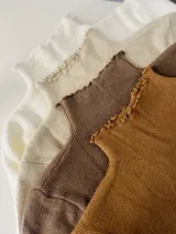 Polera de cuello alto con volados en el cuello, de tejido de punto fino en colores blanco, beige, marrón, mostaza y negro.