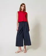 Camisa cropped sin mangas de algodón elástico con motivo de pliegues con efecto plisado, cierre con botones en tono a juego y corte recto.