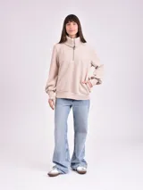 Buzo color beige con cuello alto y cierre metálico parcial.