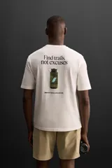Camiseta color crudo de corte relaxed fit, cuello redondo y manga corta. Estampado con la frase "Find trails, not excuses" en el frente.