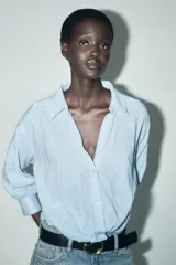 Camisa blanca de cuello solapa y manga larga con puños. Tiene un nudo en la parte delantera y cierre frontal con botones.