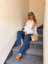 Camisa blanca con bordados florales y bolsillo dorado en el pecho.