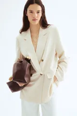 Blazer color crema de lino con doble botonadura, solapas de muesca y bolsillos delanteros ribeteados con solapa. Forrado.