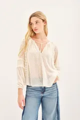 Camisa de manga larga color crudo, confeccionada en viscosa plumeti. Posee cuello redondo con tajo delantero y volados verticales.