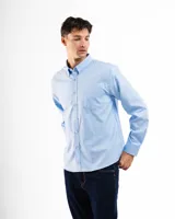 Camisa celeste de corte clásico, con cuello abotonado, manga larga y bolsillo en el pecho.