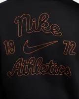 Campera negra con capucha y cierre frontal, con logo de Nike bordado en blanco en el puño izquierdo y una letra N grande en el pecho con borde naranja y relleno azul.