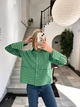 Camisa verde con rayas verticales azules, de corte recto y manga larga.