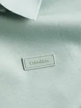 Chomba color verde claro de corte slim, cuello clásico con solapa de dos botones, mangas cortas con puños de punto, aberturas laterales y logo tonal de Calvin Klein en el pecho. Confeccionada en algodón orgánico.