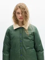 Campera verde con cuello beige de pana, largo a la cadera, con elástico inferior para ceñir a gusto. Cierre por botones a presión, bolsillos frontales y forro de cuerpo estampado de algodón.