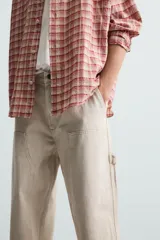 Pantalón gris de corte relaxed fit, con cinco bolsillos, efecto lavado, aplicación de tira y bolsillo multifunción en perneras. Cierre frontal con cremallera y botón.