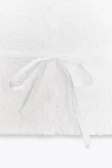 Camisa blanca de popelín con cuello solapa, manga sisa y detalle de guipur floral en el frente. Incluye un cinturón fino del mismo tejido que se ata en la cintura.